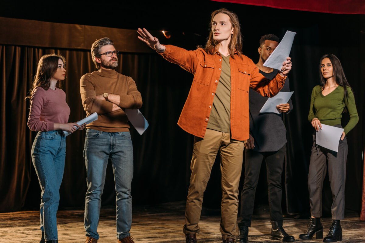 Academy of Acting multicultural actors and actresses rehearsing with scripts on stage in theatre