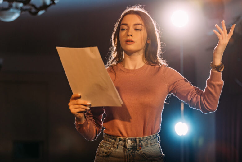 Academy of Acting young actress reading scenario on stage in theatre